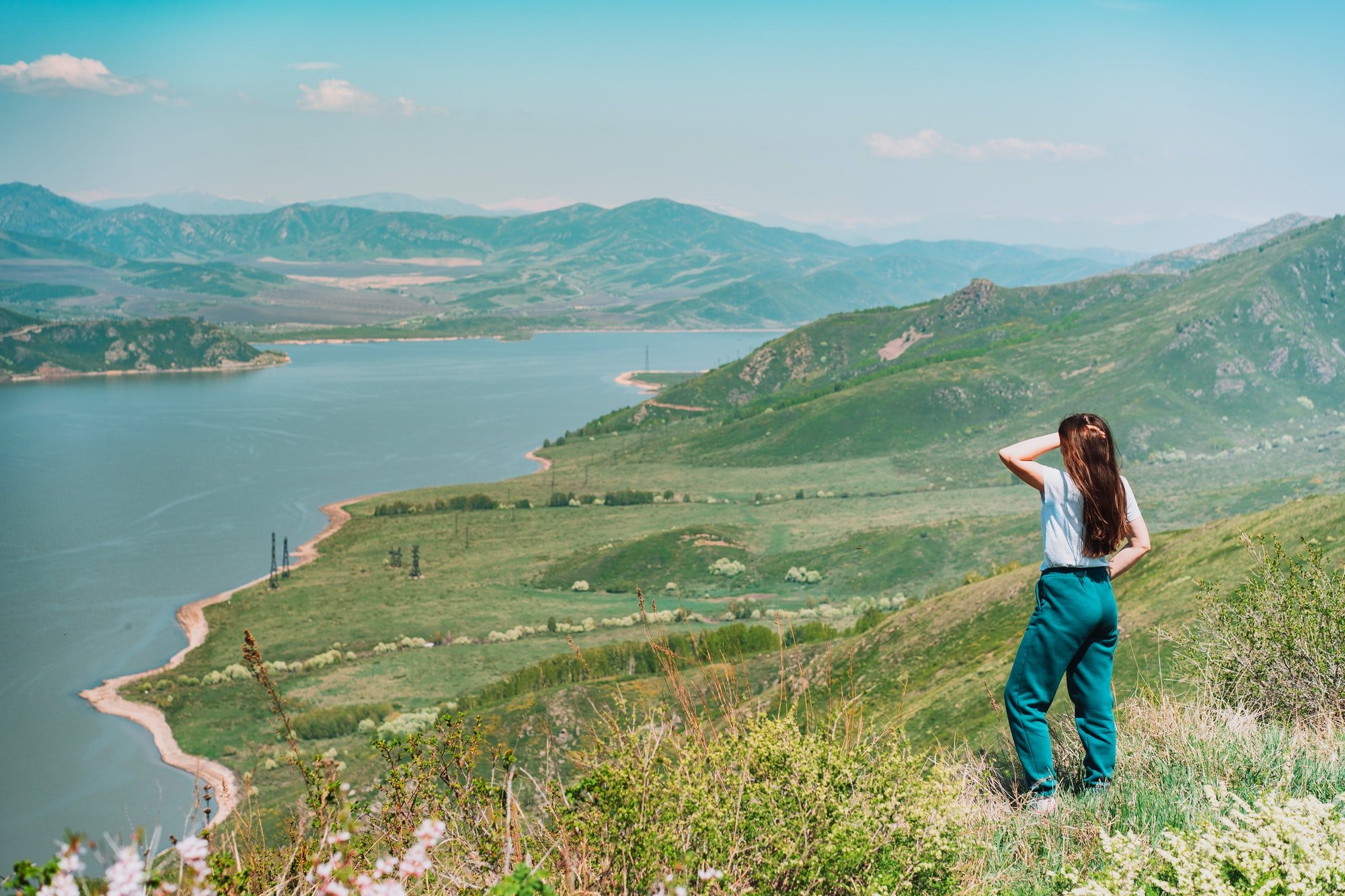 Young woman standing against blue sea and mountains background East Kazakhstan